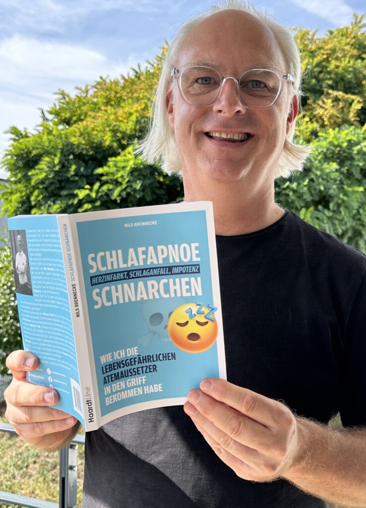 Nils Brennecke hält sein Buch Schlafapnoe Schnarchen in den Händen